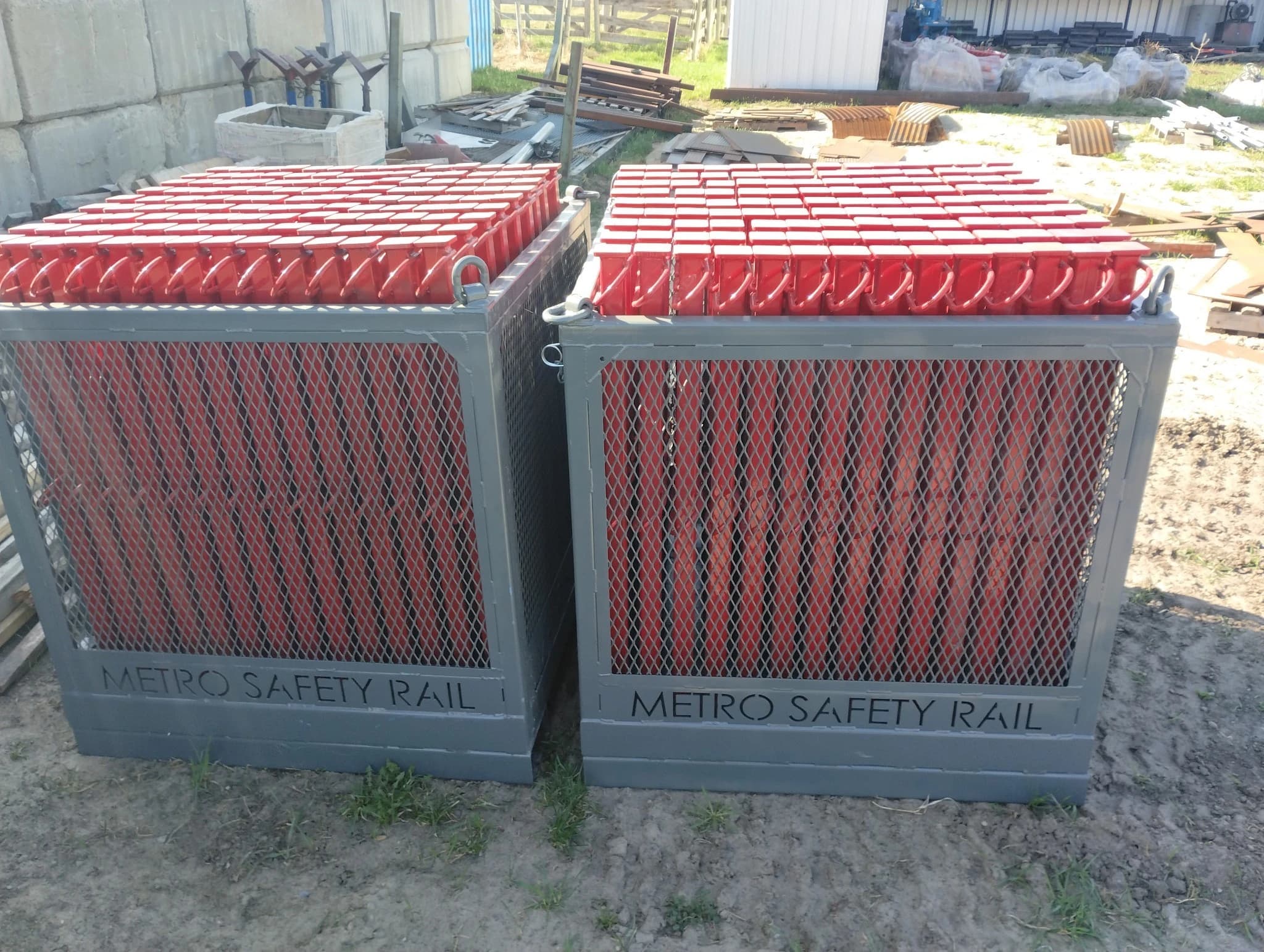 Two Metro Safety Rail transport containers branded on the panel, filled with red guardrail stanchions.