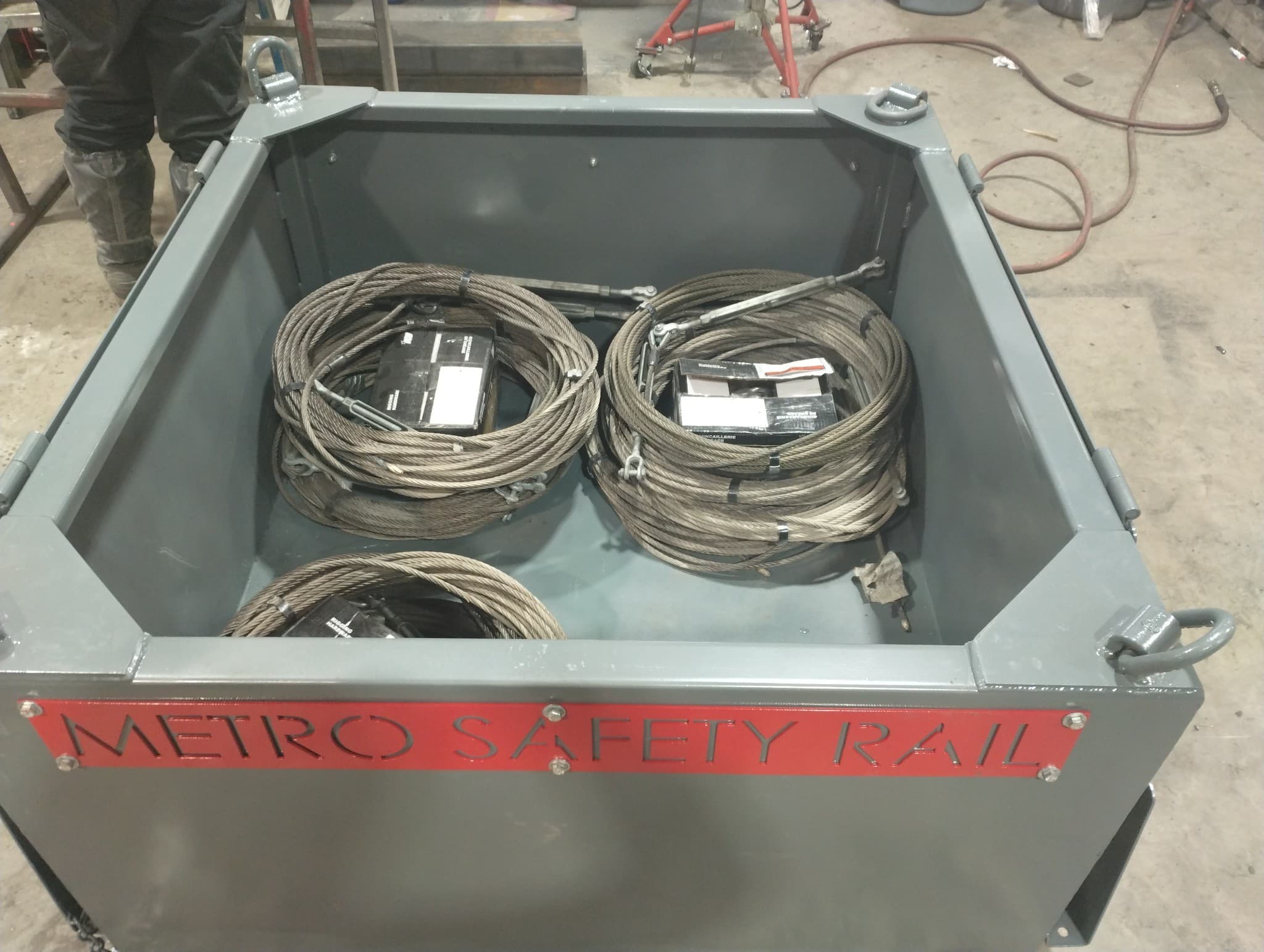 Inside a Metro Safety Rail container: coiled braided wire-rope lifelines and tensioning hardware staged for transport.